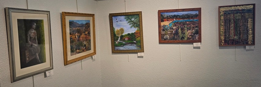 Gallery wall with five framed paintings including landscapes and mixed media